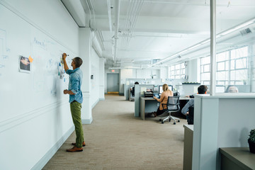 Man writing on whiteboard in office
