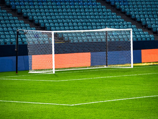 White goal post on football playing arena at empty chairs rows background