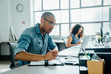 Man holding pen using laptop in office