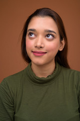 Young beautiful Indian woman against brown background