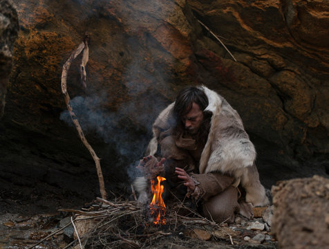 portrait of frostbitten man in animal skins near a tent on the background of the sea
