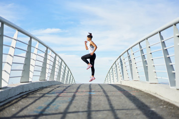 Young fit urban woman working out on a city walkway jogging