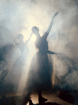 Ballerinas dancing on scene in darkness