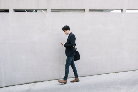 Young businessman using his cell phone on the street