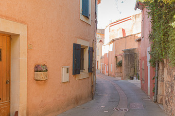 A narrow street in the beautiful French village of Roussillon, where the buildings are made with colorful.