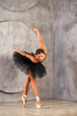 Fototapeta na wymiar Full body portrait. Russian ballerina in a black dancing suit is posing in dark studio
