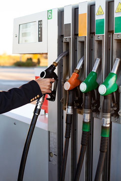 Close-up of a men's hand using a fuel nozzle at a gas station