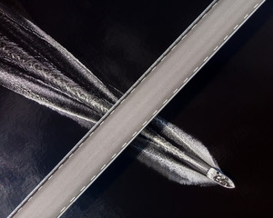Top down view of a speedboat passing under a bridge