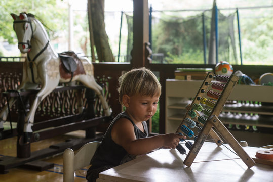 Child Counting The Beads On An Abacus