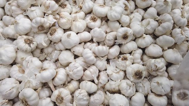 Real time of person of african ethnicity selecting garlic bulbs, allium, sativum, from a market stall