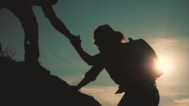 teamwork help business travel silhouette slow motion video concept. Helping hand silhouette between two climbers. teamwork group of tourists lends a helping hand climb the cliffs mountains. couple man