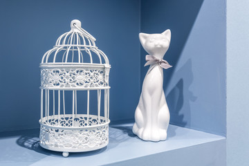 ceramic cat and metal cage in the recess of the blue wall in the apartment