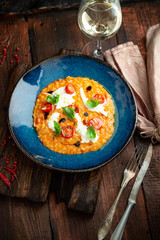 Risotto with tomatoes, Basil, cheese and olive oil on a blue plate. Italian national cuisine, rustic style