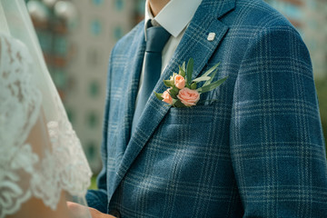 A small bouquet of flowers near the groom's jacket pocket. Close up picture of best man's boutonniere on wedding day