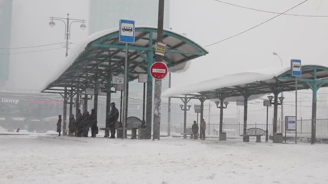 people waiting bus during heavy snofall
