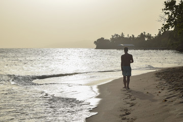 Naklejka premium Man walking on the beach into the sunset