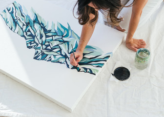 Side shot of female asian illustrator working on painting in studio space