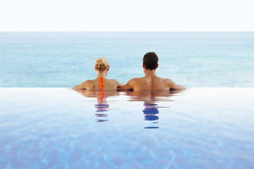 Romantic couple looking at the ocean from infinity pool