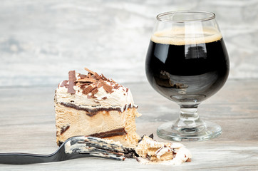 Fork has sliced a bite from a n ice cream cake with a cold beer