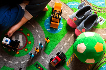 Kid playing with toy cars on road map carpet
