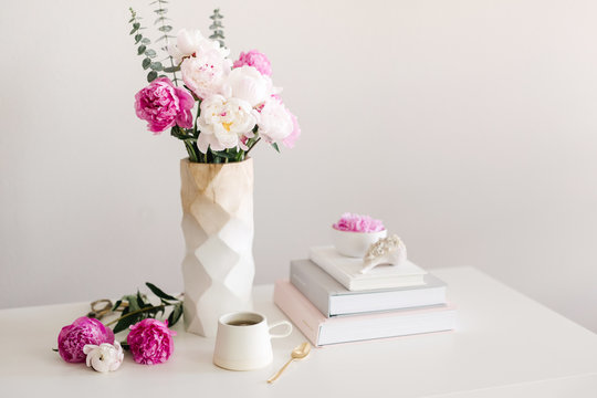 spring peonies, tea, and books on a desk
