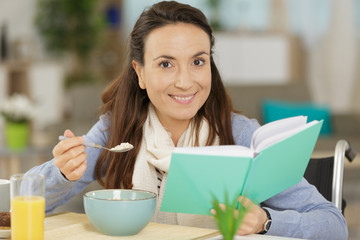 portrait of charming female reading while eating lunch