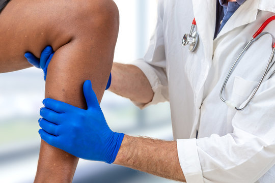 Close-up image of male doctor cheking knee of male patient