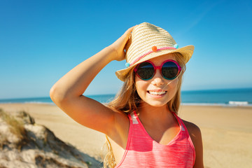 Beautiful girl in sunglasses and holding straw hat