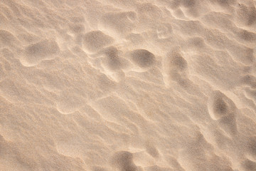 Fototapeta na wymiar Beach sand texture with step marks. Smooth yellow sand surface card. Sandy seashore top view photo. Tropical beach