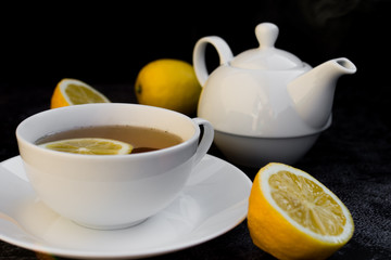Teapot and cup of tea with fresh lemon.