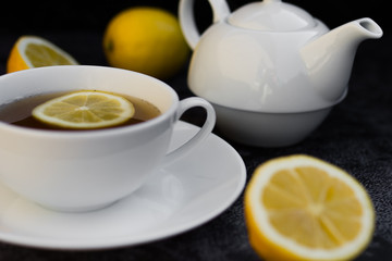 Teapot and cup of tea with fresh lemon.