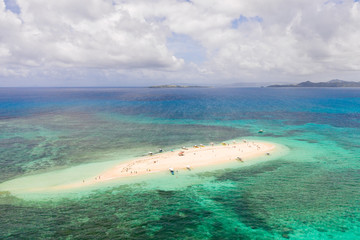 People relax on a tropical island and swim in the lagoon. Naked Island, Siargao. Tourists came to the white island in boats. White sandy island.