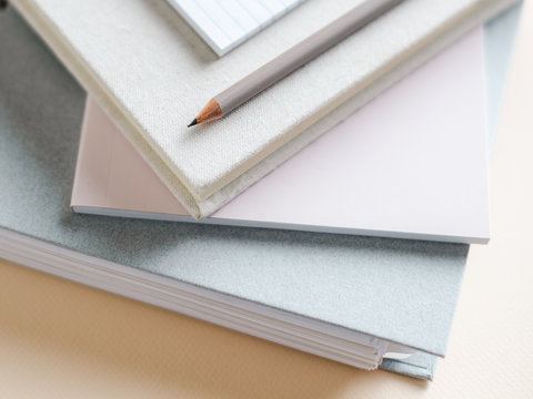 Stacked notebooks and pencil