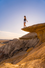 Lifestyle of a young blonde in the Bardenas Reales on top of a stone with open arms, Navarra. Spain
