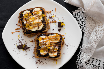 Toast with chocolate cream and bananas, decorated butterscotch and grated chocolate
