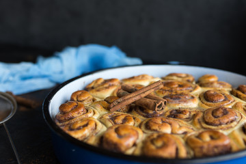 Cinnamon roll tart with sugar syrup in vintage baking pan on black background