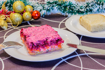 Dressed herring or herring under a fur coat. Symbol of the new year. Traditional Russian cuisine. Christmas decorations in the background. New Year's concept.