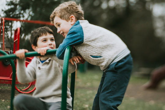 Two brothers playing on merry go round