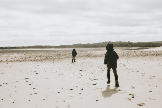 Two brothers running along empty beach