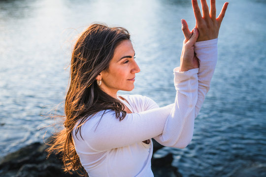Young woman doing yoga on the rocks at golden hour