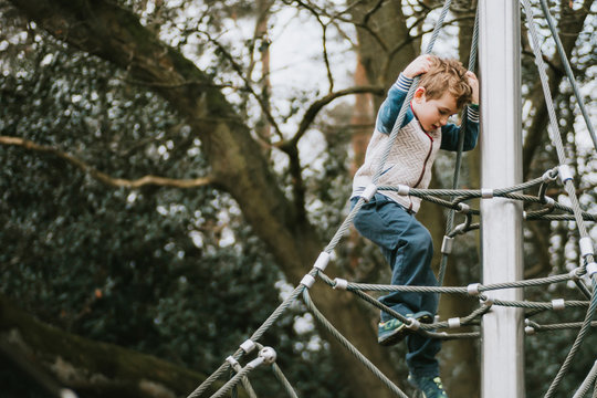 Side view of boy climbing down climbing frame