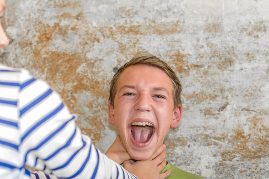 The girl strangles the boy, and he raised his hands up and can not breathe.  Production photo.