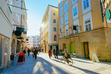 Obraz premium Kobieta na rowerze na ulicy starego miasta Salzburga