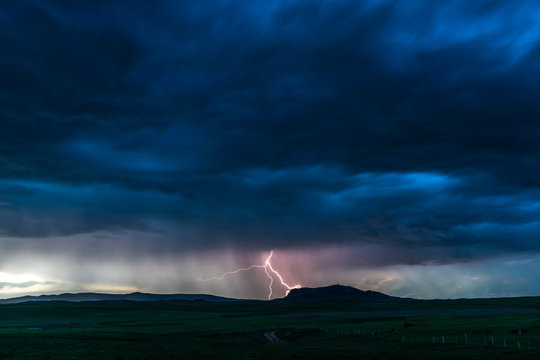 Dark cloudy sky with lightning bolt in the middle hitting the ground