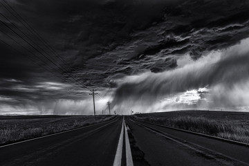 Heavy storm and cloudy sky over road and farm fields, black and white