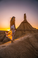 Blonde girl with white dress and flowers on a sunset at the Castildestones de las Bardenas. Navarre