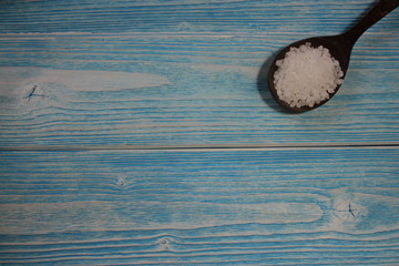 Spoon with sea salt on wooden background.