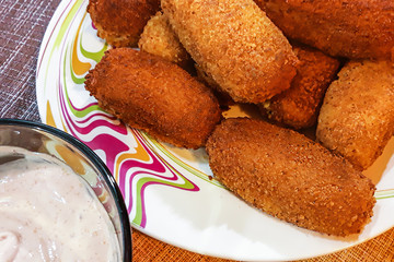 Deep-fried chicken nuggets with spicy sauce on a brown background