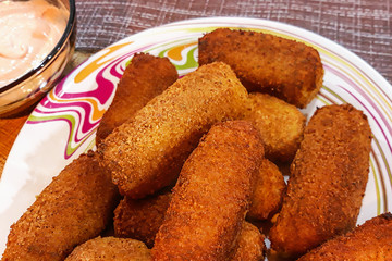 Deep-fried chicken nuggets with spicy sauce on a brown background