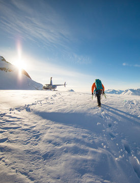 Mountaineer approaches his helicopter, waiting on a glacier